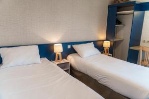 two beds sitting next to each other in a room at Brit Hotel Argentan in Argentan