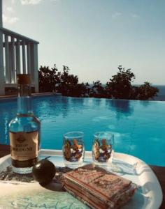 a bottle of wine and two glasses on a table by a pool at Villa Vigie in Deshaies