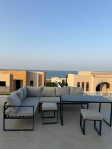 a couch and a table and chairs on a patio at Beach front 414 villa private pool in Muscat