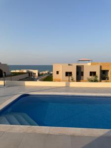 a swimming pool in front of a house and the ocean at Beach front 414 villa private pool in Muscat