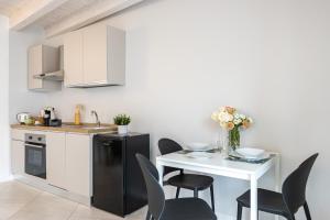 a kitchen with a white table and black chairs at Al Castello - fresco e ben isolato appartamento in Calolziocorte