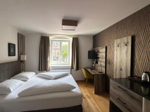 a bedroom with two beds and a desk and a window at Hotel Goldener Löwe in Kufstein