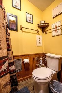 a bathroom with a toilet and a yellow wall at The Lodge in Helen +7 photos
