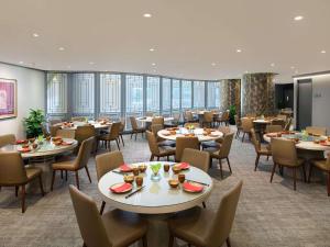 a dining room with tables and chairs and windows at Grand Mercure Singapore Roxy in Singapore