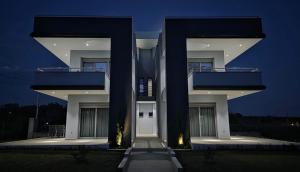 a large white building with two levels at night at Pearl Luxury Suites in Paralia Dionysiou