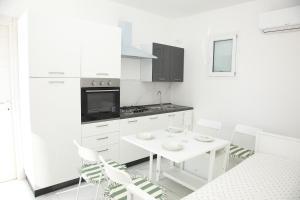 a white kitchen with a white table and chairs at Ama affittacamere in Gleris