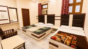 a room with two beds and a chair in it at Hotel Marwari in Agra