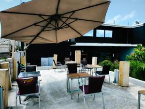 a patio with tables and chairs and an umbrella at O'soho GarDens BingerVille in Bingerville