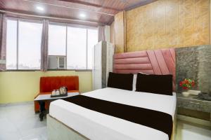 a bedroom with a bed and a desk and window at HOTEL O RAJDHANI in Kānpur