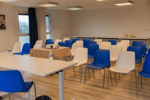 a room with tables and chairs and blue chairs at Brit Hotel Argentan in Argentan