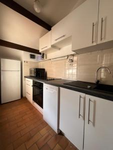 a kitchen with white cabinets and a black stove top oven at Azurea in Saint-Cyr-sur-Mer