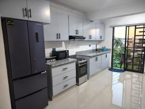 a kitchen with white cabinets and a black refrigerator at Beautiful View Apartment in San Pedro de Macorís