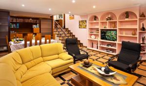 a living room with a yellow couch and chairs at Villa Rosal in Oia