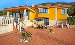 a yellow house with a patio and table and chairs at Villa Rosal in Oia
