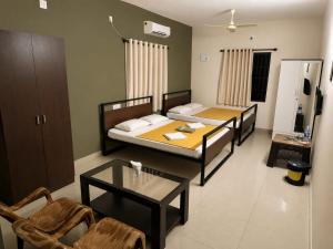 a living room with two beds and a table at Shyams homestay MV in Malpe