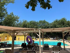 a group of chairs under a pavilion next to a swimming pool at Domaine Les Chênes Blancs in Saint-Saturnin-lès-Apt