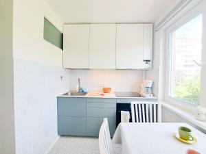 a kitchen with white cabinets and a table and a window at Cozy Vintage Apartment in Klaipėda