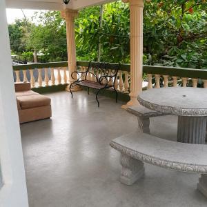 a porch with two benches and a table and chairs at Hospedaje de la playa in Sámara