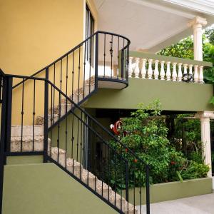 a staircase with a green and black railing at Hospedaje de la playa in Sámara