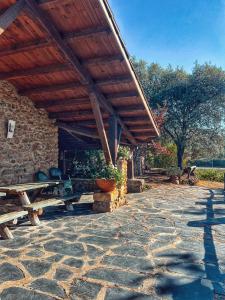 a pavilion with a table and benches on a stone patio at La Simona Casa Rural in Perales del Puerto
