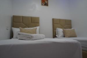 a bedroom with two beds with white sheets and pillows at Studio MLK in Chefchaouen
