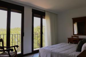 a bedroom with a bed and a balcony with windows at La Posada del Conde in Ardales +13 photos