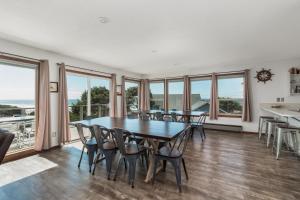 a dining room with a table and chairs and windows at Captain Johns in Lincoln City