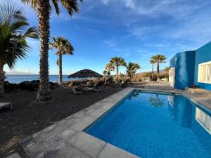 a swimming pool with palm trees and the ocean at Cap-Azul in Porto Novo