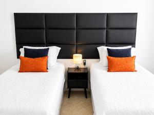 two beds with orange and blue pillows in a room at Beachfront Condo on Boardwalk in Philipsburg