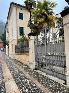 a fence with a palm tree next to a building at Casa delle Rose - Appartamento Dagape in Marostica
