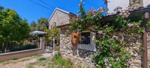 a stone building with flowers on the side of it at Sundial Stone House in Ždrelac
