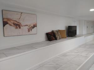 eine weiße Galerie mit Gemälden an der Wand und einem Fernseher in der Unterkunft Quiet Ocean View Open Concept, Loft Style Studio within Forested Area, Near Parks & Ferry in Nanaimo