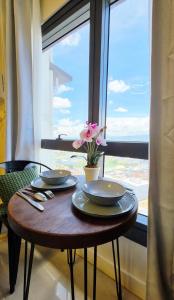 a table with two plates and a vase with a flower on it at The View at 34th - Sunset Skyline Suite Near SM J Mall & Fiber Wifi in Mandaue City