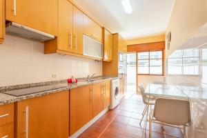 a kitchen with wooden cabinets and a table and chairs at Refúgio do Mar -Steps from the Beach- in Armação de Pêra
