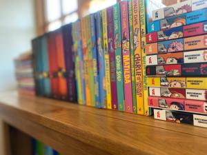 a row of books sitting on a wooden shelf at 8 BR Luxury Farmhouse | Tennis Court & EV Charging in Tile Hill +37 photos
