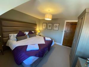 a bedroom with a large bed with purple sheets at 8 BR Luxury Farmhouse | Tennis Court & EV Charging in Tile Hill