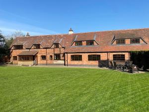 a large brick building with a green lawn in front of it at 8 BR Luxury Farmhouse | Tennis Court & EV Charging in Tile Hill