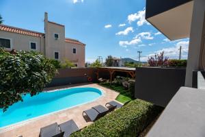 a swimming pool with lounge chairs in a backyard at DreamCoast Apartments I in Artemida