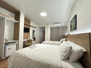 a bedroom with a large white bed and a television at Zallon Hotel Executivo - Late Checkout Cortesia as 15hs aos DOMINGOS in Lajeado