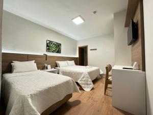 a hotel room with two beds and a television at Zallon Hotel Executivo - Late Checkout Cortesia as 15hs aos DOMINGOS in Lajeado