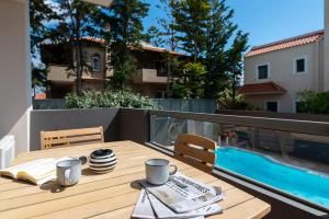 a table on a balcony with a book and coffee cups at DreamCoast Apartments I in Artemida
