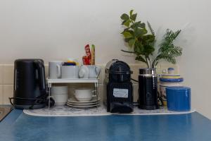 a shelf with a coffee maker and cups and a plant at 2nd Floor 1-Bedroom Apartment in Urangan