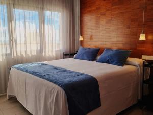 a bedroom with a large bed with blue pillows at Apartamentos El Arrecife in Conil de la Frontera