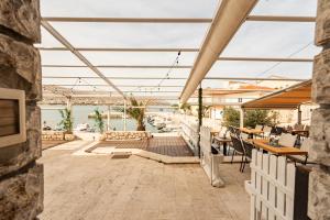 a patio with tables and chairs and a view of the water at Laguna Rooms in Pag