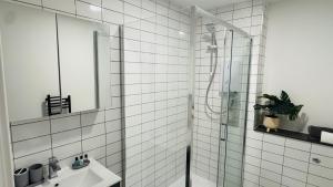 a white tiled bathroom with a shower and a sink at Central Old Town 1-Bed Apartment in Swindon