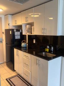 a kitchen with white cabinets and a black refrigerator at Ocean View Apartment In Sunny Isles in Sunny Isles Beach