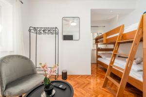 a room with a chair and a desk and bunk beds at Laguna Rooms in Pag