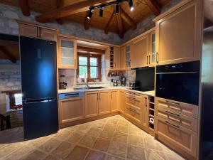 a kitchen with wooden cabinets and a black refrigerator at Villa Ionis in Volímai