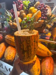 a person holding up a drink in a wooden cup at Pousada Berimbau in Arraial d'Ajuda