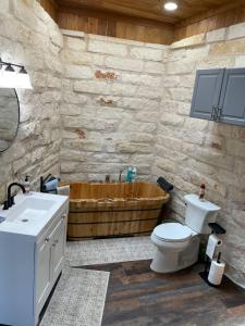 a bathroom with a toilet and a wooden tub at The Cross Patio Retreat in Buda